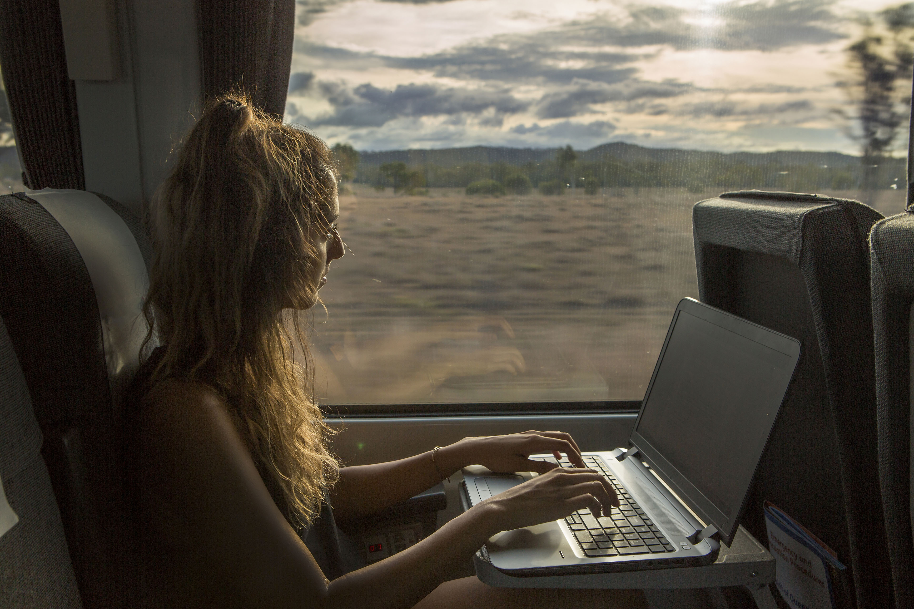 A woman works on her laptop while traveling on a train